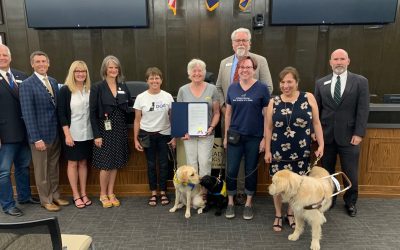 Photo with 10 adults, 2 puppies in training and one service dog receiving the colorado proclamation