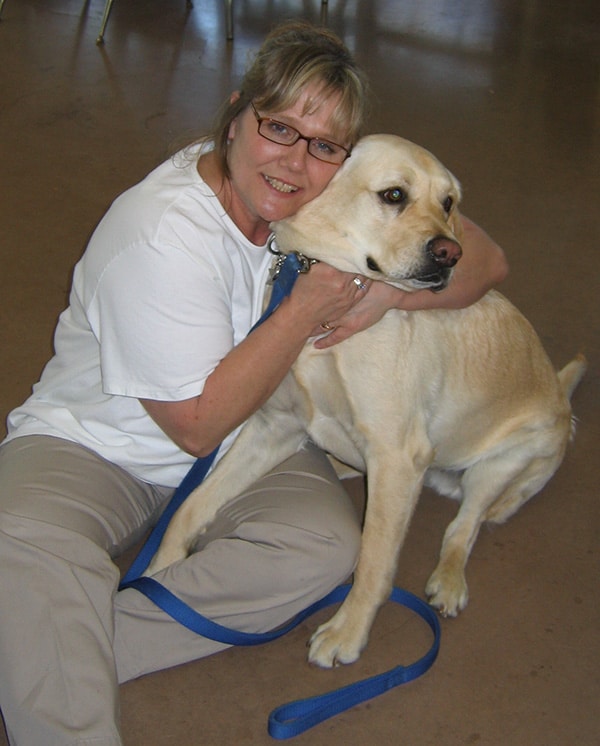 a woman hugs a yellow lab