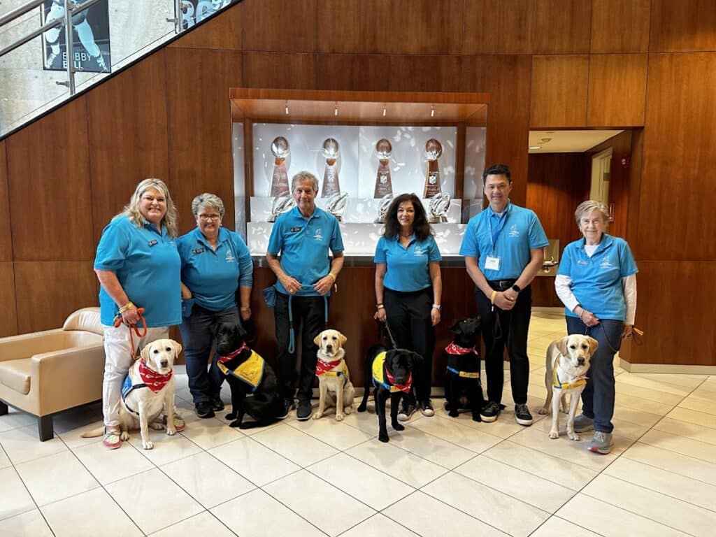 Heartland Volunteer Chapter members visit the Kansas City Chiefs and pose in front of a trophy case.